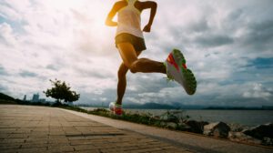 Fitness woman running training for marathon on sunny coast trail